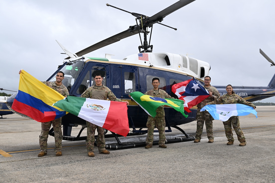 Members assigned to the 1st Helicopter Squadron pose in front of a UH-1N Huey helicopter with flags representing their Hispanic and Latino heritage at Joint Base Andrews, Md., Sept. 17, 2024. This gathering celebrated their diverse backgrounds in honor of the squadron's first recorded all-Hispanic and Latino flight during National Hispanic Heritage Month, recognized across the Department of Defense annually from Sept. 15 - Oct. 15. (U.S. Air Force photo by Airman 1st Class Gianluca Ciccopiedi)