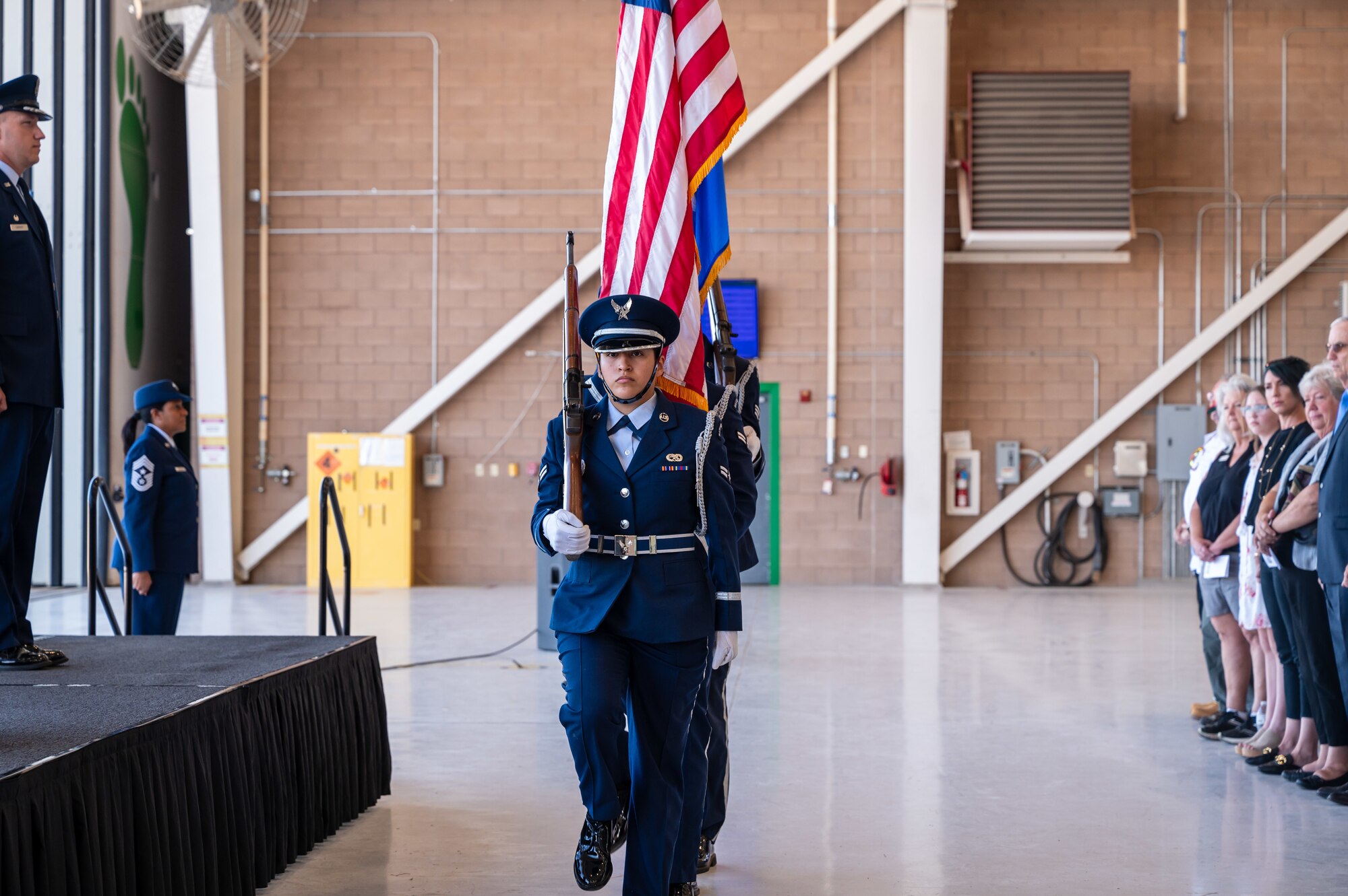 People in military dress uniforms carry rifles and flags