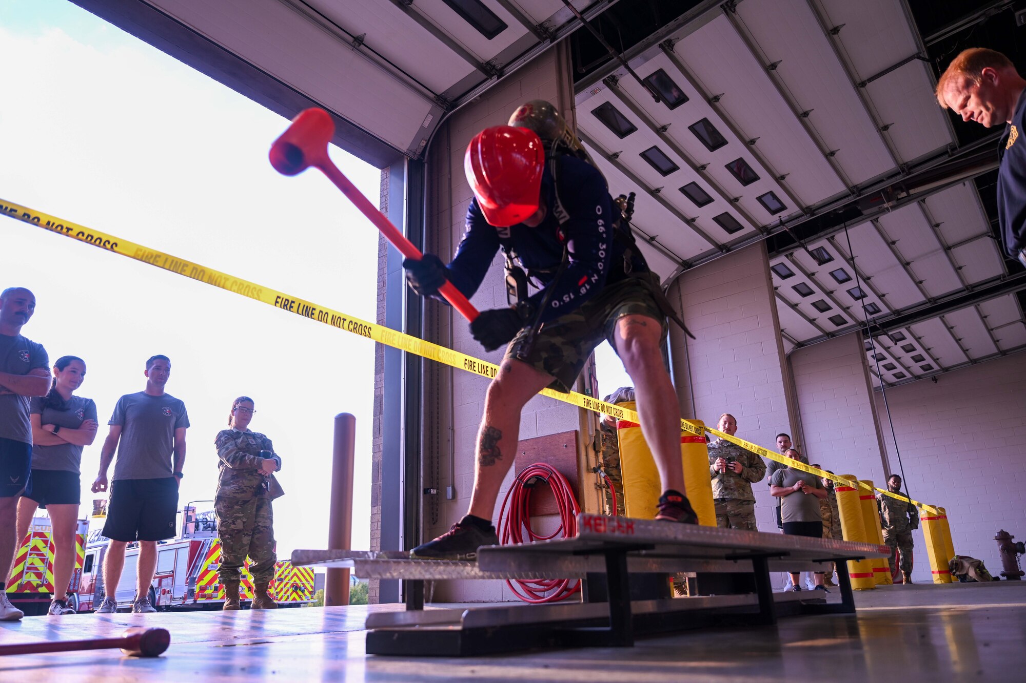An Airman from the 722nd Maintenance Squadron swings a mallet during the annual 22nd Civil Engineer Squadron Fire Muster Oct. 10, 2024, at McConnell Air Force Base, Kansas. The Fire Muster consisted of five teams competing for the fastest time to complete various tasks such as unrolling a large fire hose, dragging a dummy and spraying a fire hose at a target. (U.S Air Force photo by Senior Airman William Lunn)