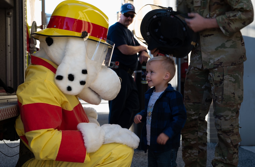 Sparky, the Fire Prevention Week mascot, greets a young Team Dover member during a Fire Prevention Week open house at Dover Air Force Base, Delaware, Oct. 10, 2024. The open house took place during Fire Prevention Week, a nationally observed week used to educate people on fire prevention. (U.S. Air Force Photo by Dieondiere Jefferies)