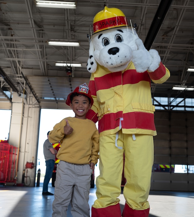 Sparky, the Fire Prevention Week mascot, poses for a photo with a young Team Dover member during an open house at Dover Air Force Base, Delaware, Oct. 10, 2024. The open house took place during Fire Prevention Week, a nationally observed week used to educate people on fire prevention. (U.S. Air Force Photo by Dieondiere Jefferies)