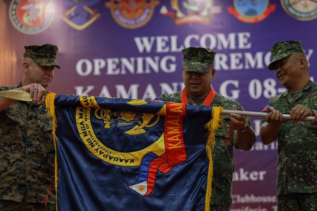 From left, U.S. Marine Corps Col. Stuart Glenn, commanding officer for Marine Rotational Force-Southeast Asia, Philippine Marine Corps Maj. Gen. Arturo G Rojas, commandant of the Philippine Marine Corps, and Philippine Marine Corps Brig. Gen. Vicente Map Blanco III, director, exercise directorate headquarters, unfurl the KAMANDAG exercise flag during the opening ceremony for KAMANDAG 8 at Fort Bonifacio, Manila, Philippines, Oct. 15, 2024. KAMANDAG is an annual Philippine Marine Corps and U.S. Marine Corps-led exercise aimed at enhancing the Armed Forces of the Philippines’ defense and humanitarian capabilities by providing valuable training in combined operations with foreign militaries in the advancement of a Free and Open Indo-Pacific. This year marks the eighth iteration of this exercise and includes participants from the French Armed Forces, Royal Thai Marine Corps, and Indonesian Marine Corps; including continued participation from the Australian Defense Force, British Armed Forces, Japan Ground Self-Defense Force, and Republic of Korea Marine Corps. MRF-SEA is a rotational unit executing a Marine Corps Forces Pacific operational model that involves training events and exchanges with partner military subject matter experts, promotes security goals with Allied and partner nations, and ensures a persistent I Marine Expeditionary Force presence west of the International Date Line.  (U.S. Marine Corps photo by Cpl. Tyler Wilson)
