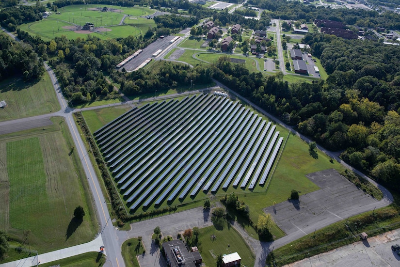 An aerial view shows a solar panel array near various buildings.