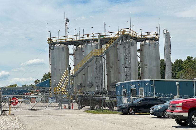 Large towers sit at behind a fence at an industrial site.