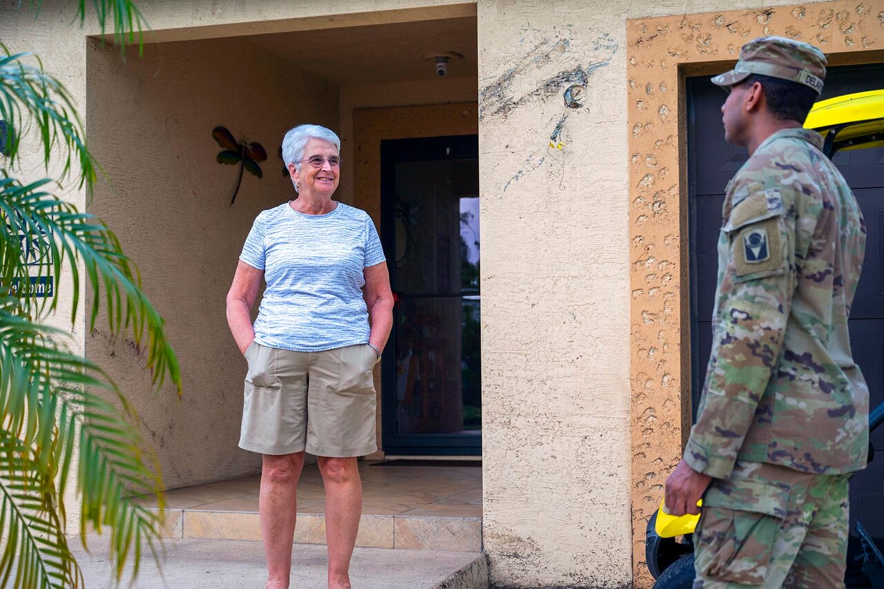 A soldier talks with a resident at the front of their home.