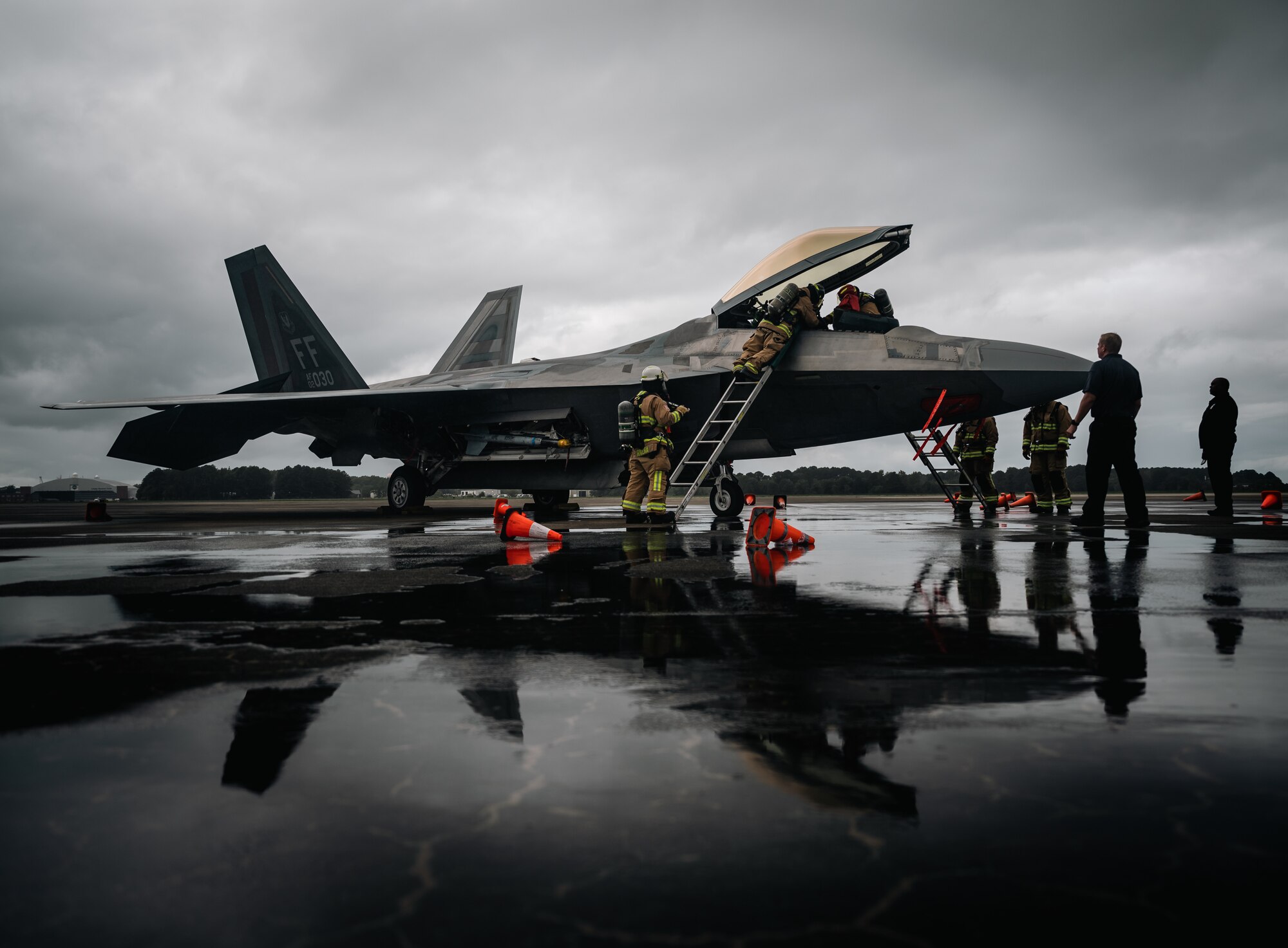 Firemen surround an F-22 in stormy weather