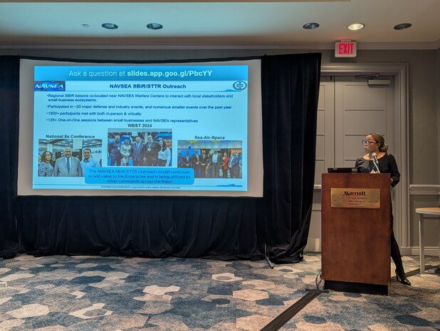 A woman stands at the podium presenting during the Small Business Symposium at the North Bethesda Marriott Hotel and Conference Center.