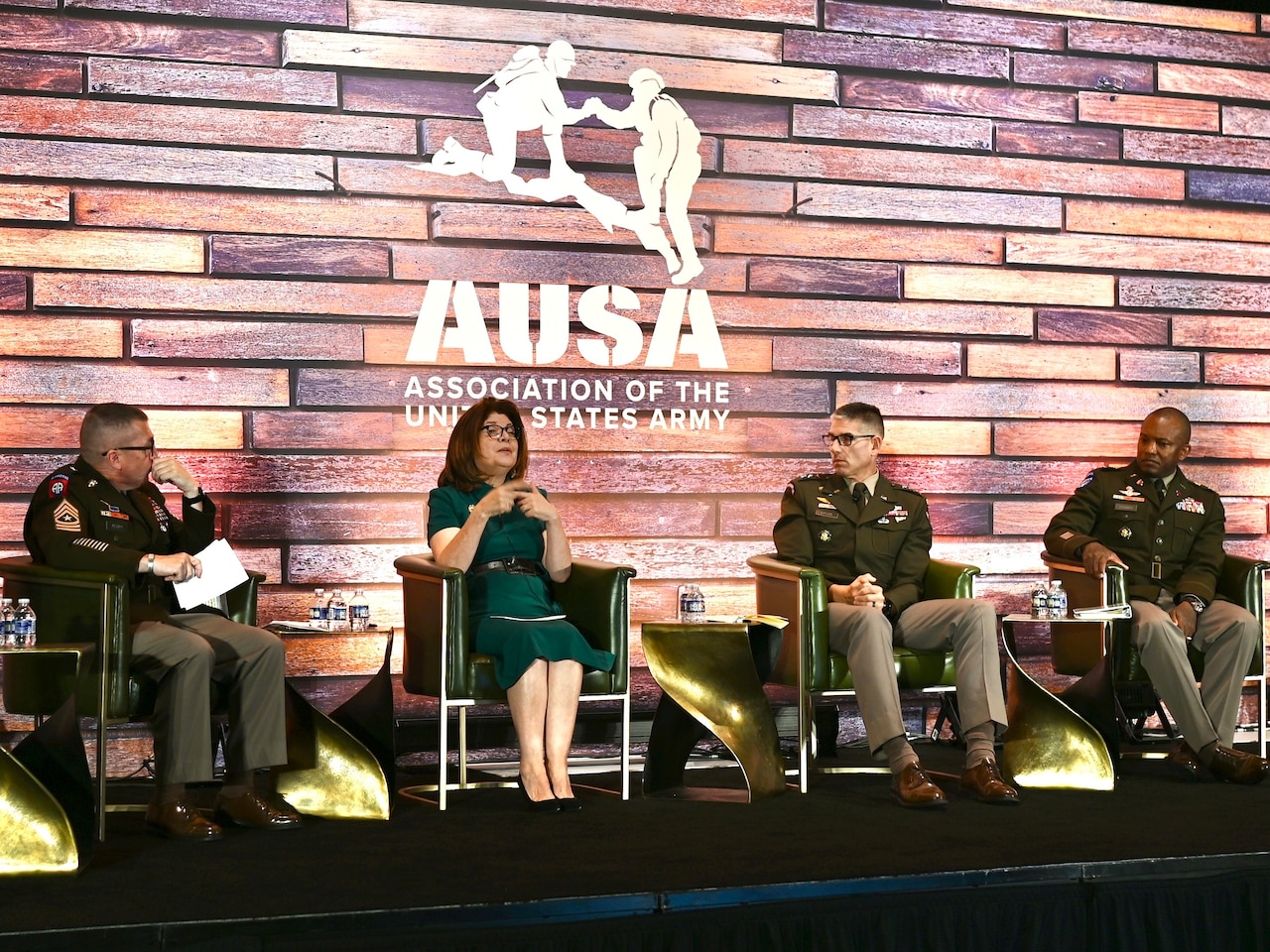 A woman on a panel speaks alongside three uniformed service members.