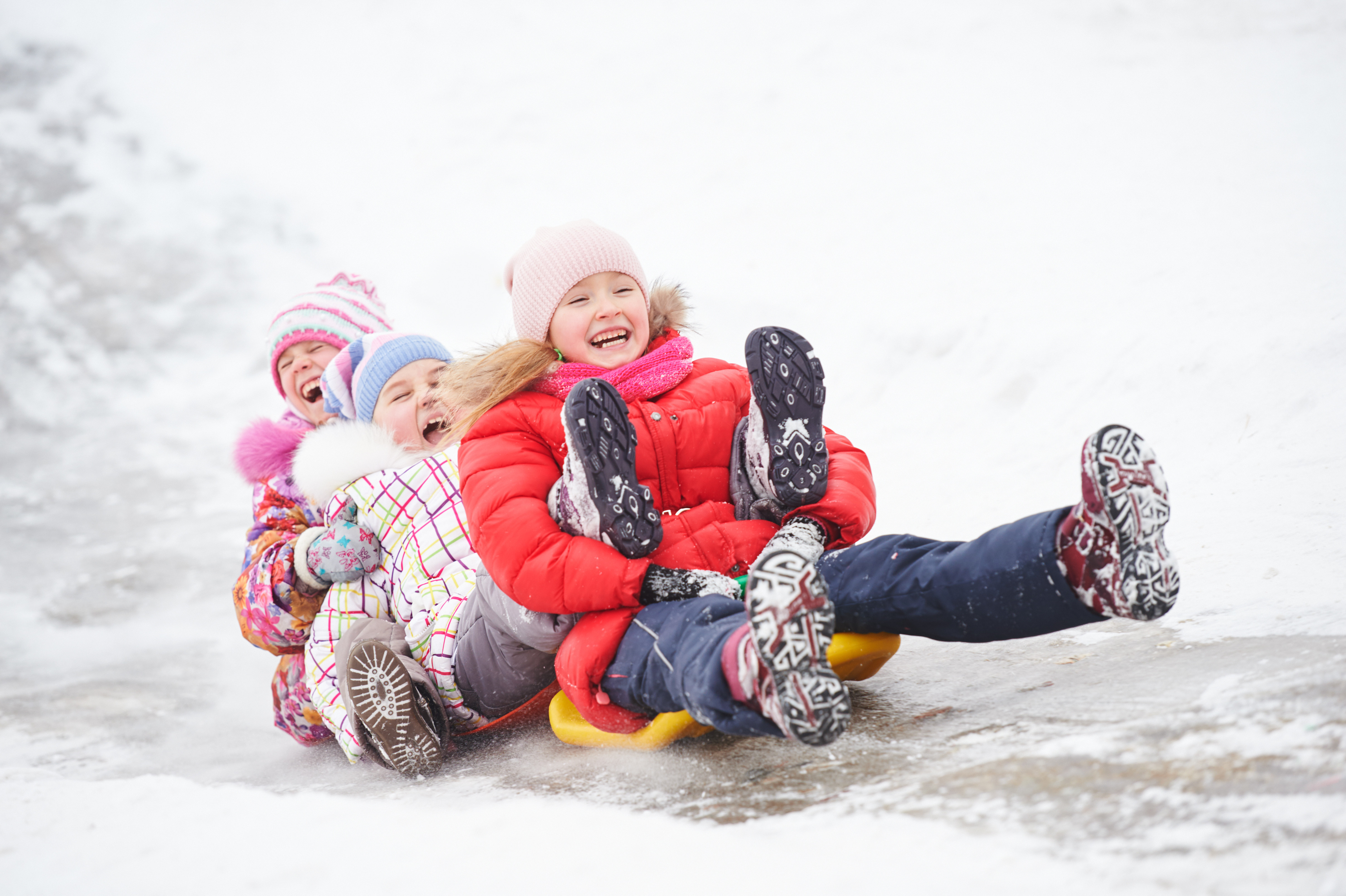 Three children sledding on snow