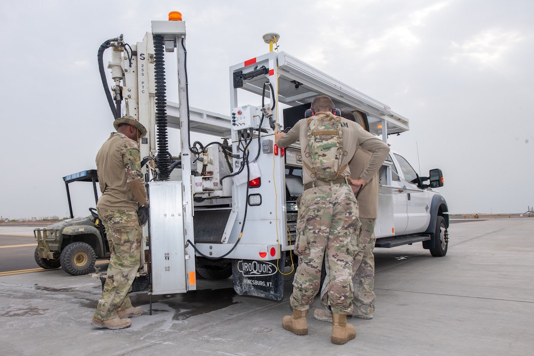 Airmen use a machine to extract a core pavement sample on a runway