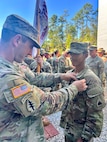 U.S. Army 1st Lt. Andrew Devine, left, pins Air Assault wings on his son, U.S. Army Pfc. Isaiah Castellanos, during a graduation ceremony at Fort Moore, Ga., on Sept. 20, 2024. Upon completion of Air Assault School each soldier is able to perform skills required to make maximum use of helicopter assets in training and in combat to support mission objectives.