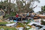 A soldier hugs a civilian among debris.