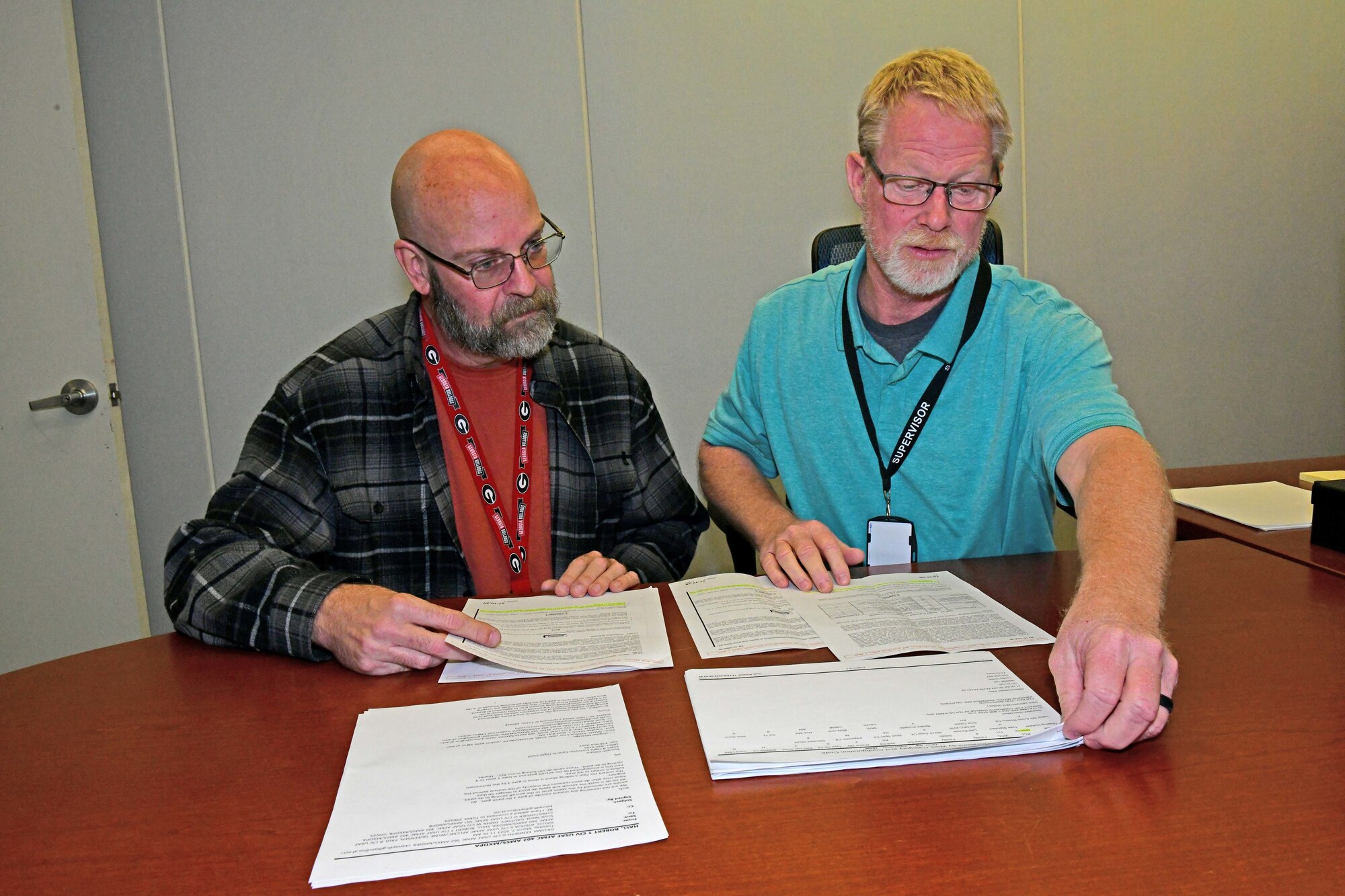 Two men sitting down while looking at documents on table