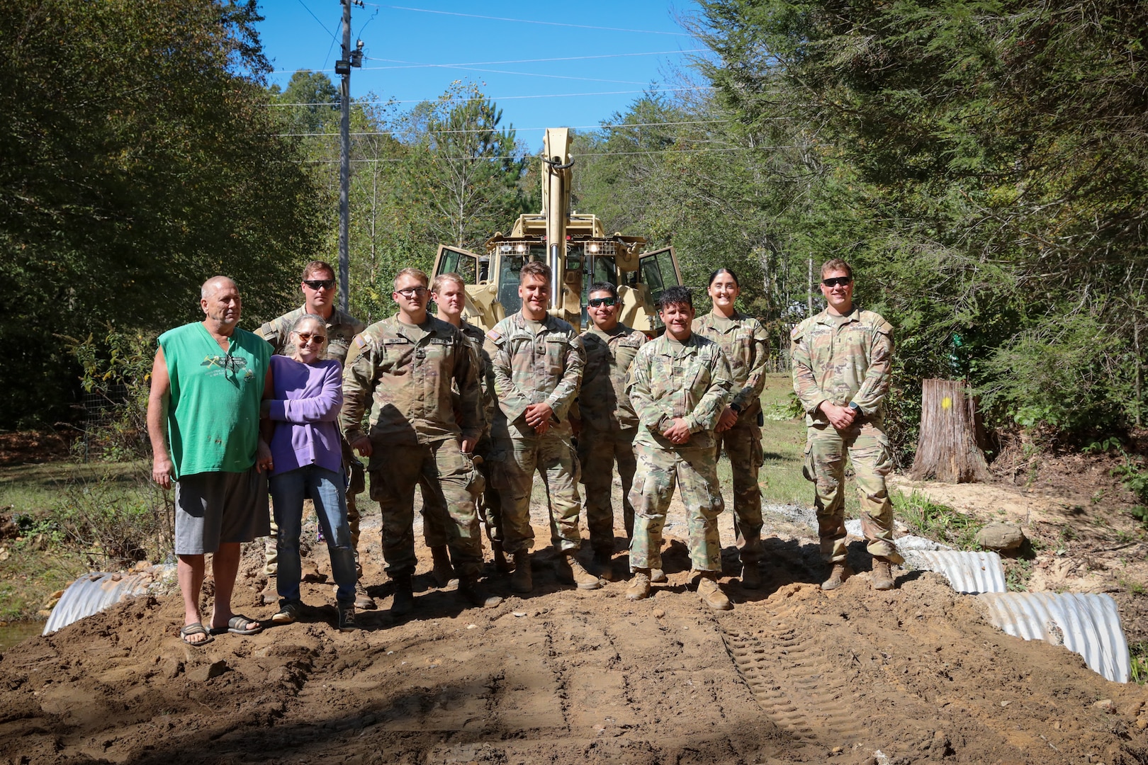 North Carolina National Guardsmen with the 113th Sustainment Brigade and the 30th Armored Brigade Combat Team pose for a photo with Rick and Carla Brite after a bridge-building operation at their residence in Nebo, N.C., Oct. 9, 2024. Guardsmen built bridges to connect roads for local residents following Tropical Storm Helene.