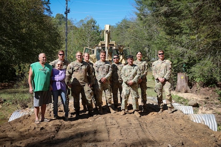 North Carolina National Guardsmen with the 113th Sustainment Brigade and the 30th Armored Brigade Combat Team pose for a photo with Rick and Carla Brite after a bridge-building operation at their residence in Nebo, N.C., Oct. 9, 2024. Guardsmen built bridges to connect roads for local residents following Tropical Storm Helene.