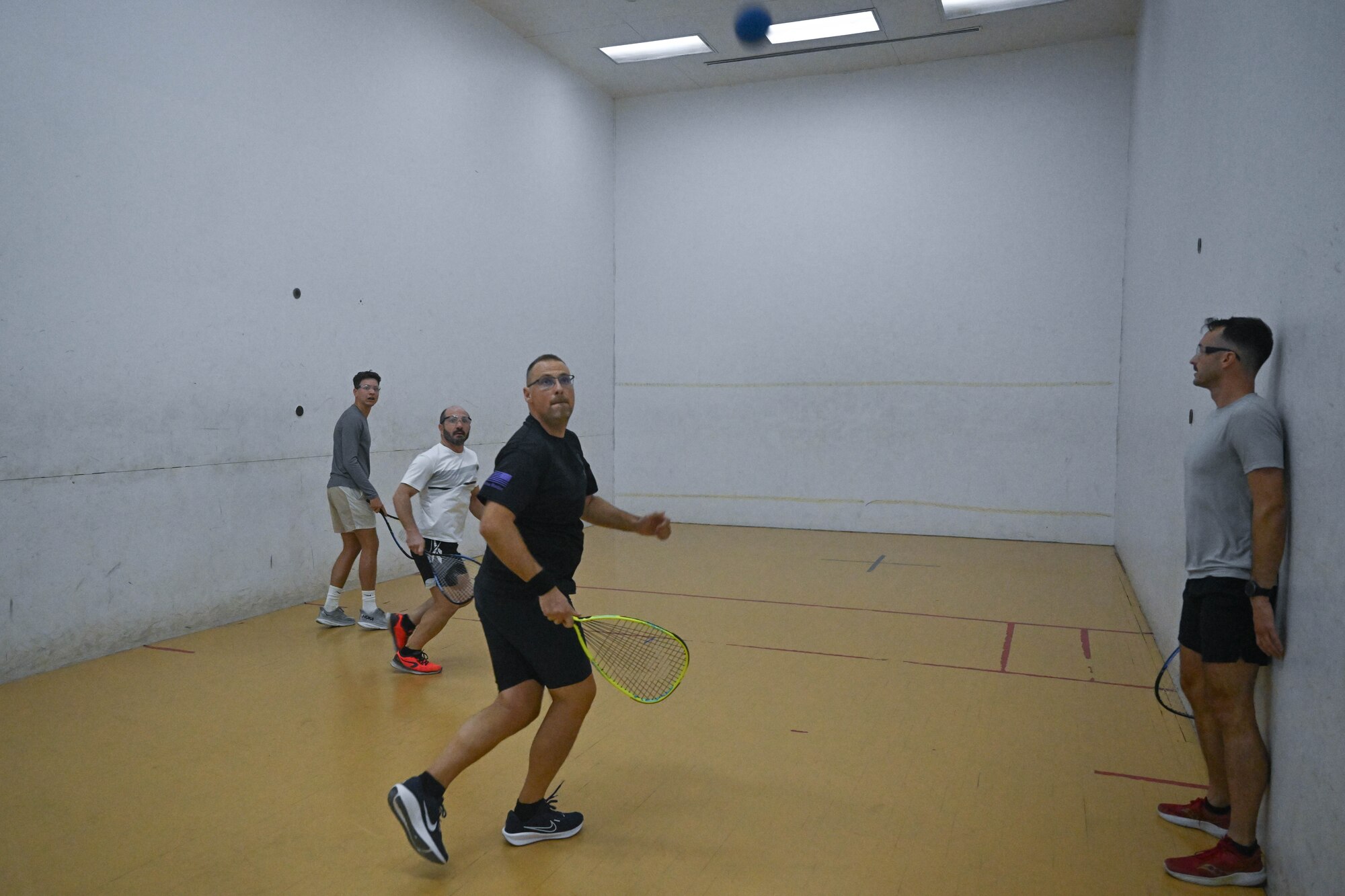 Four men play racquetball together.