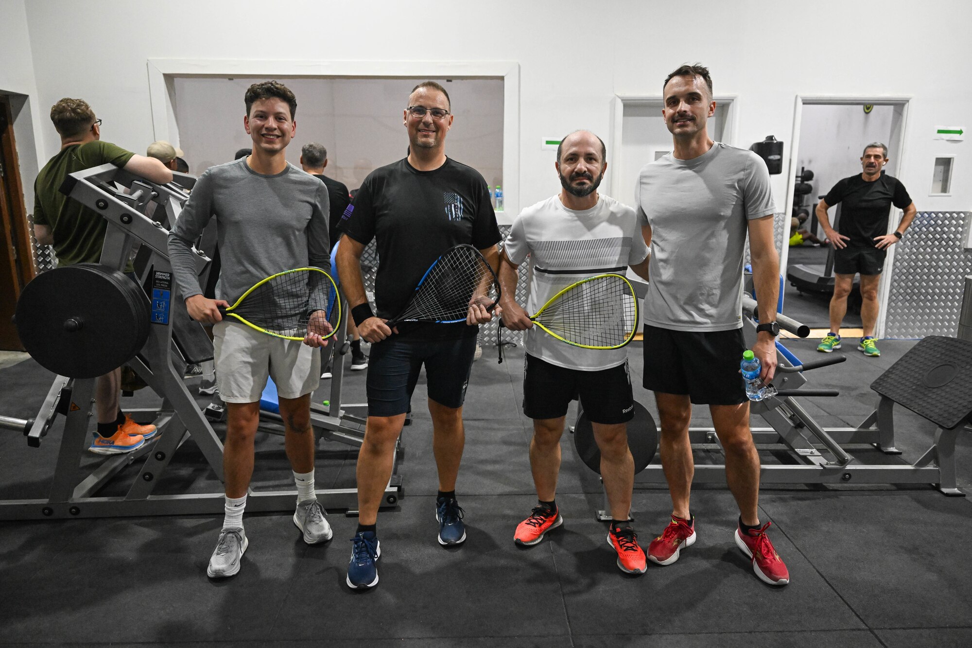 A group of men pose for a photo holding racquetball equipment.