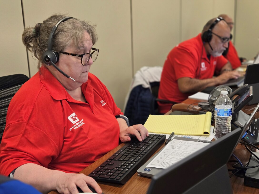 U.S. Army Corps of Engineers employees are pictured in front of their computers with headsets on to take emergency calls from people impacted by Hurricane Milton.