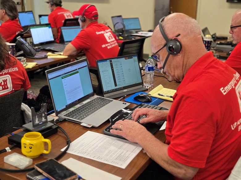 U.S. Army Corps of Engineers employees are pictured in front of their computers with headsets on to take emergency calls from people impacted by Hurricane Milton.