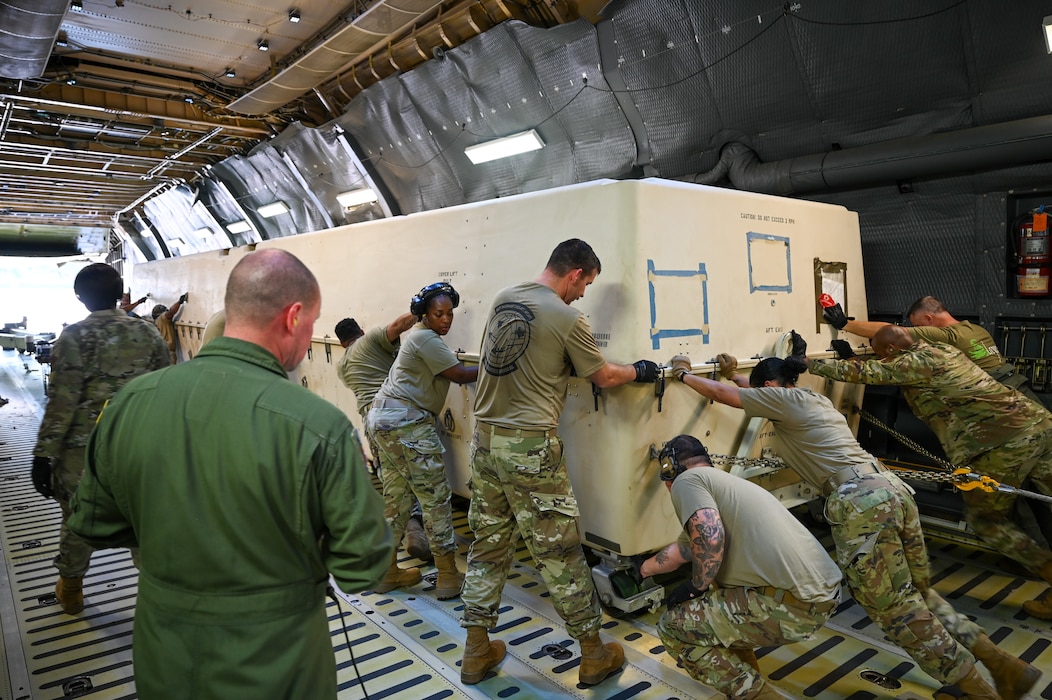 68th Airlift Squadron aircrew members and Airmen from the Texas Air National Guard’s 147th Attack Wing, help push an aircraft cargo container holding a MQ-9 Reaper on Sept. 28, 2024.