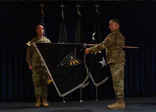  U.S. Space Force Colonel Andrew Menschner, Mission Delta 31 commander and Chief Master Sgt. Joshua Griffin, MD 31 senior enlisted leader, unfurl the ceremonial guidon during a redesignation ceremony at Peterson Space Force Base, Colo., Oct. 15, 2024. During the ceremony the Position, Navigation and Timing (PNT) Provisional Delta was officially redesignated as Mission Delta 31. The new MD 31 flag includes components such as the Polaris star and southern cross, which represent centuries of humanity looking to the stars for navigation, as well as its critical role in driving the course of progress, then, now and in the future.(U.S. Space Force photo by John Ayre)