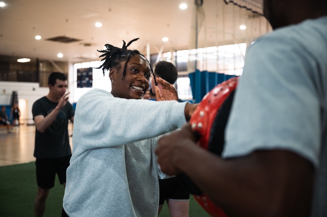 A female Airmen punches a foam while smiling