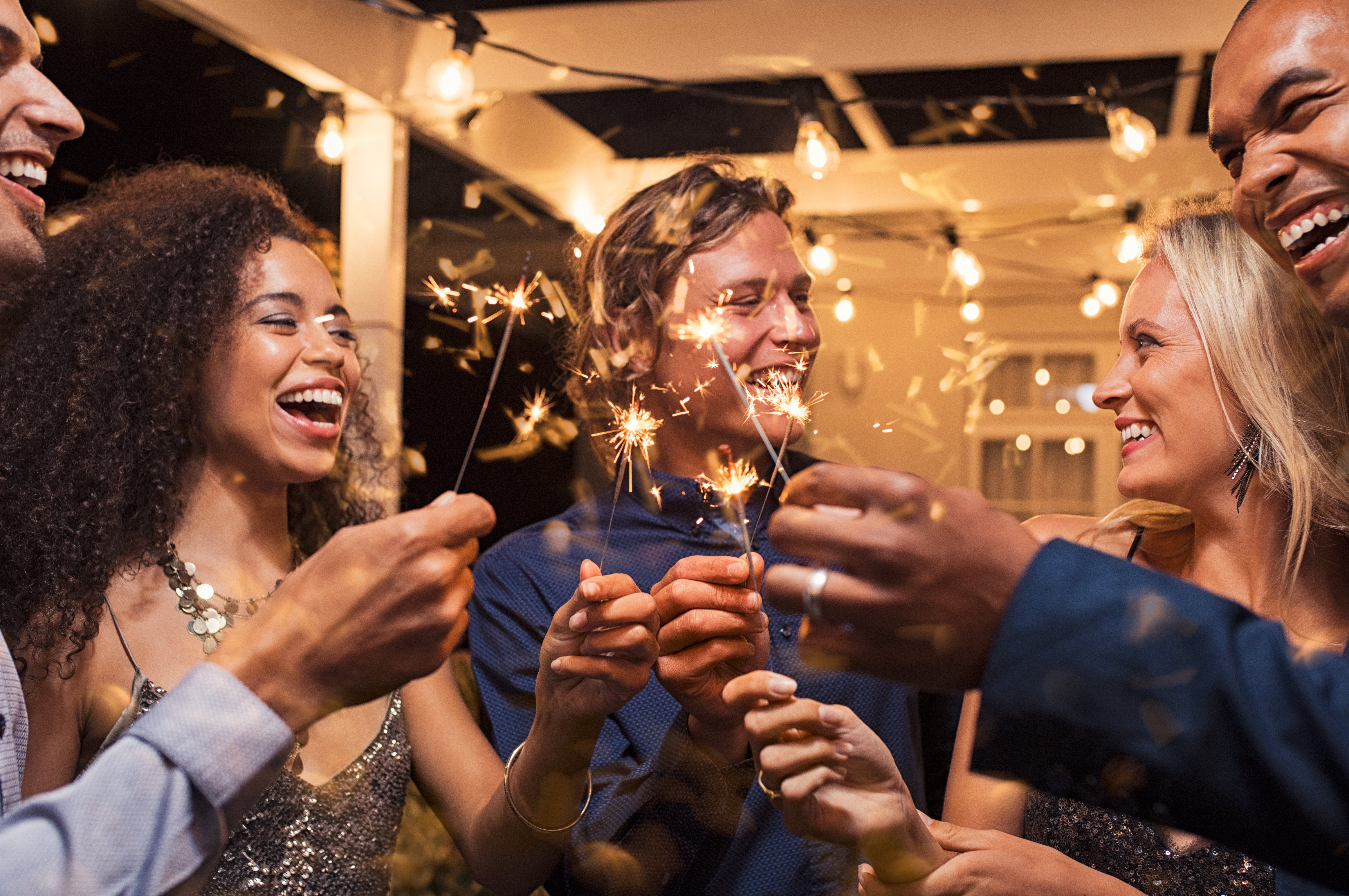 Friends celebrating Christmas with sparklers laughing outside.