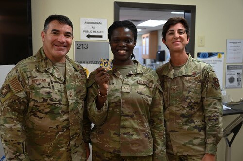 U.S. Air Force Maj. Gen. Wolfe Davidson, Second Air Force Commander, and Chief Master Sgt. Kristina Montgomery, Second Air Force Command Chief, and Senior Airman Nadialine Philippe, 17th Medical Group immunizations technician, stand together at the Ross Clinic, Goodfellow Air Force Base, Texas, Oct. 1, 2024. Davidson coined Phillippe for her contributions to the 17 MDG, Goodfellow and the community of San Angelo. (U.S. Air Force photo by Airman 1st Class Madi Collier)