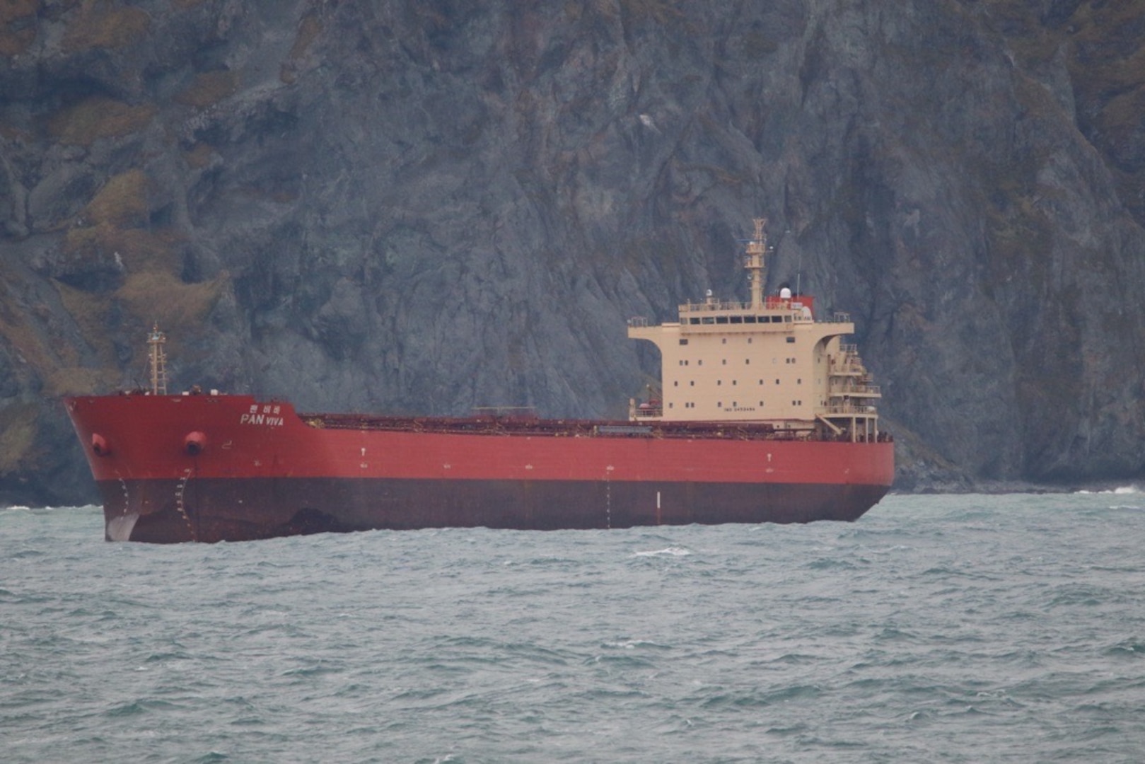 The Coast Guard continues the response, Oct. 14, 2024, to Pan Viva, a 738-foot cargo vessel, beset by weather 2.3 miles northeast of Unalaska, Alaska. Coast Guard Cutter Stratton (WMSL 752) and a tug from Dutch Harbor are on scene to assist. Pan Viva will evaluate weighing anchor as weather subsides. Coast Guard photo courtesy of CGC Stratton.