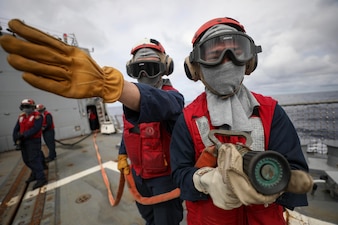 FC2 Harrison Cavanaugh, left, and LS3 Raymond Imperial man a fire hose during an aircraft firefighting drill aboard USS Dewey (DDG 105)  in the Andaman Sea.