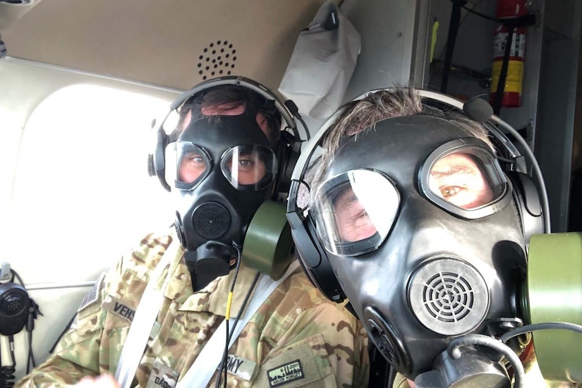 Two pilots wearing gas masks look at the camera.