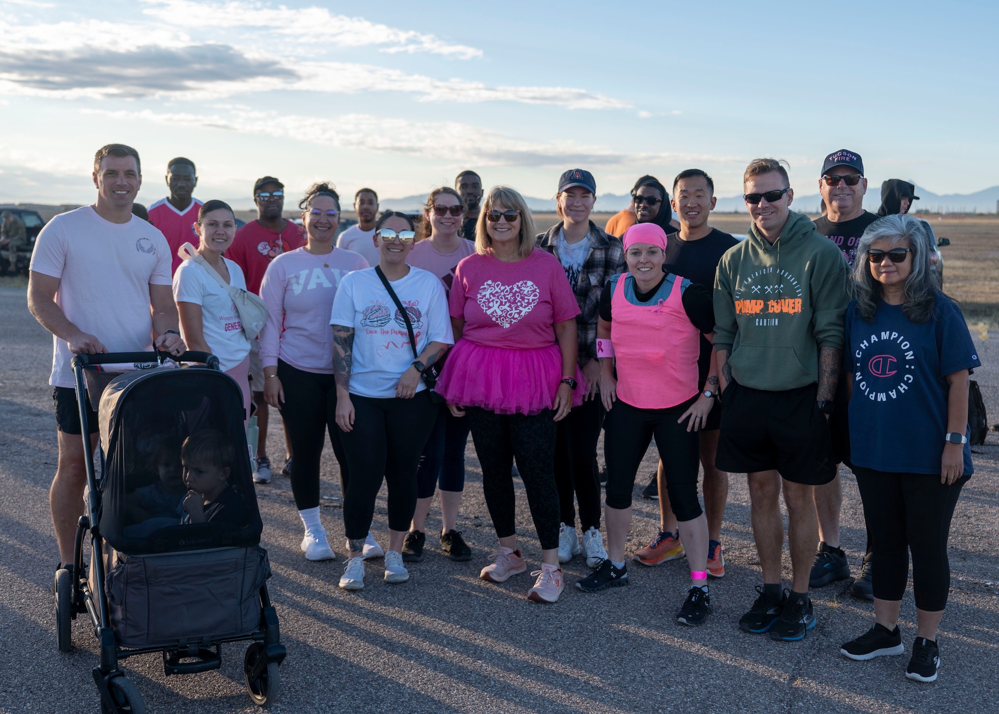 A group of people with the majority wearing pink in support of Breast Cancer Awareness month pose together for a group photo.