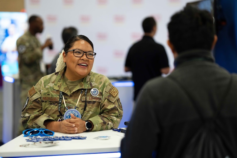 An airman smiles while talking to a civilian.