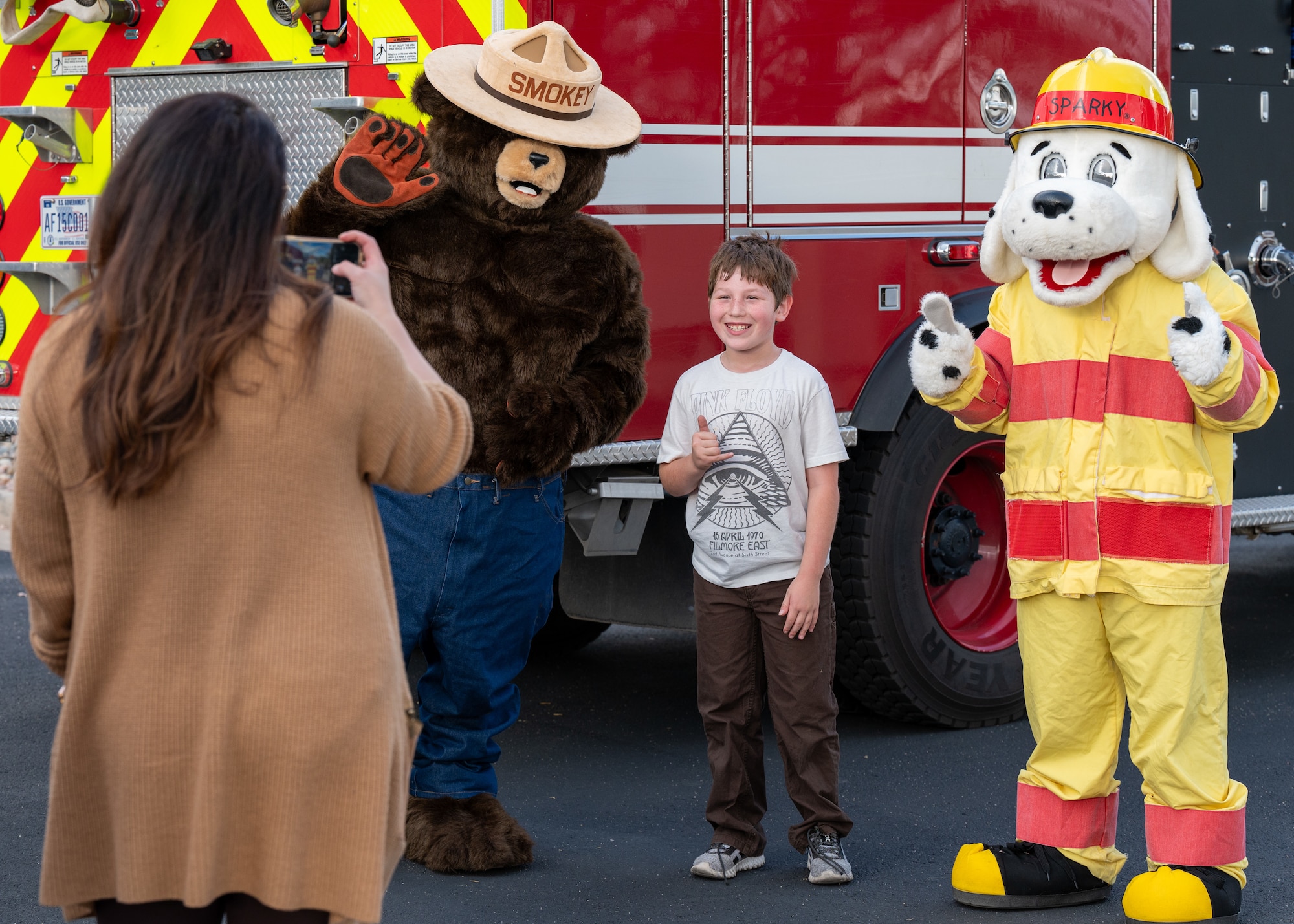 Mother takes photo of son with Smokey the Bear and Sparky the Fire Dog mascots during a Fire Prevention meet-and-greet at the U.S. Air Force Academy, Colorado, October 11th 2024.