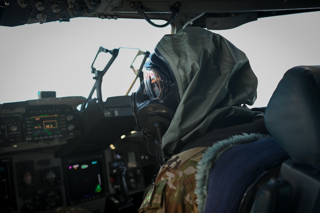 U.S. Air Force Capt. Kaitlin Winter, a pilot with the 7th Expeditionary Airlift Squadron, flies a C-17 Globemaster III from Joint Base Lewis-McChord, Washington, while wearing mission-oriented protective posture gear during a simulated nuclear contamination scenario for Exercise Rainier War 25A, over the Pacific Ocean, Oct. 11, 2024.