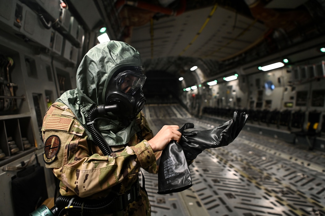 U.S. Air Force Senior Airman Helena Vanmeteren, 7th Expeditionary Airlift Squadron loadmaster, dons her mission-oriented protective posture gear in-flight during a simulated radiological contamination scenario for Exercise Rainier War 25A, during a flight over the Pacific Ocean, Oct. 11, 2024.