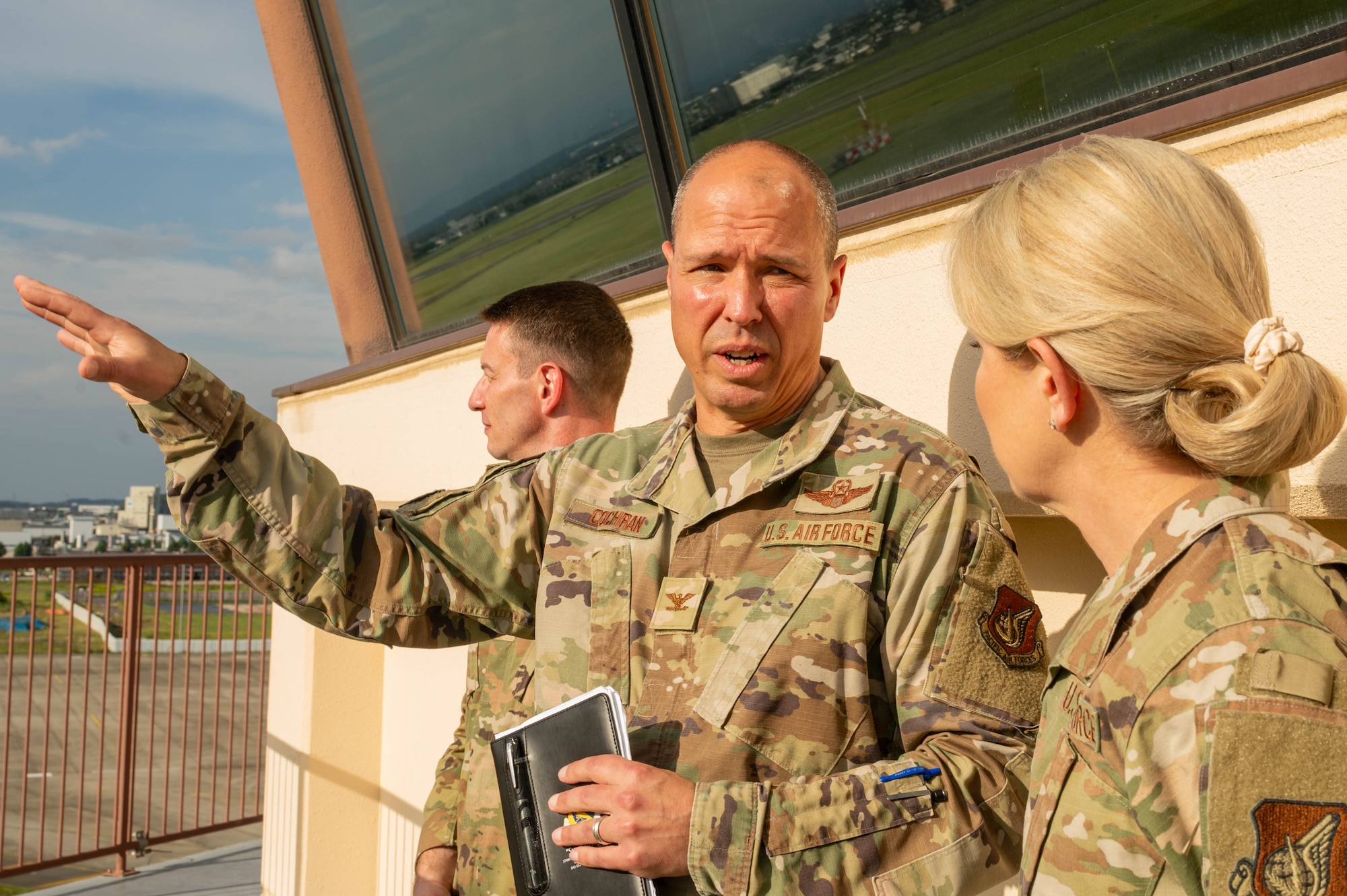 Service member talks to other service member while gesturing his hand to show the sights while on the ATC tower.