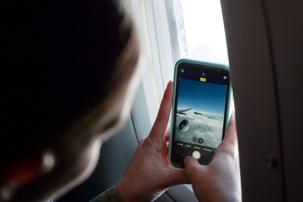 Sofia Deneny, The University of Oklahoma (OU) Naval ROTC midshipman, takes a photo of a U.S. Navy Blue Angels F/A-18 Super Hornet aircraft through the window of a KC-46 Pegasus aircraft over the skies of Texoma, Oct. 14, 2024. Deneny is a freshman at OU with the desire to become a pilot in the Marine Corps. (U.S. Air Force photo by Airman 1st Class Lauren Torres)