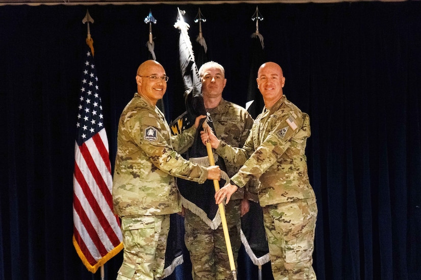 Three guardians hold the staff of a flag.