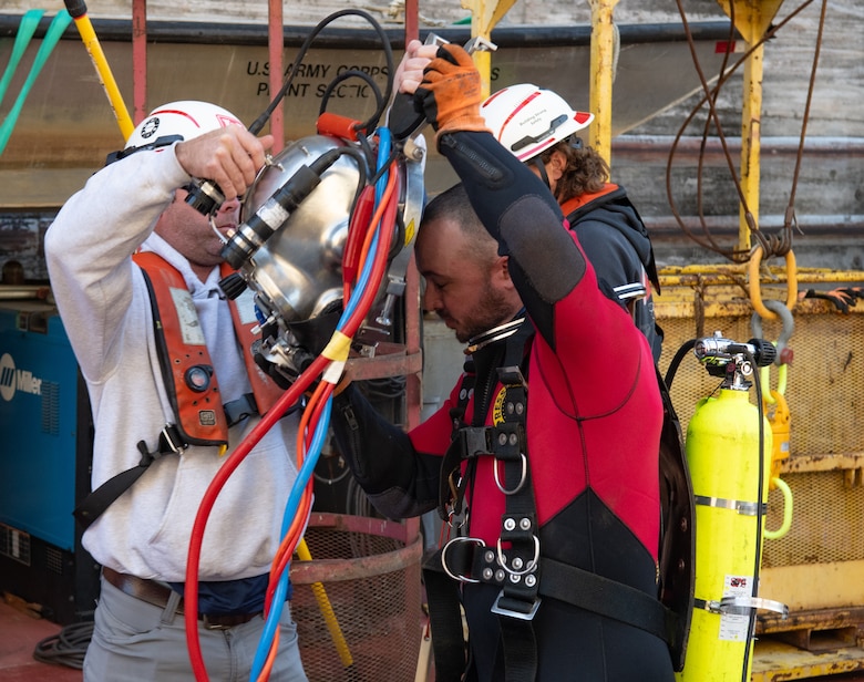 Ty Melton, a lock mechanic with the U.S. Army Corps of Engineers Nashville District, dons diving headgear with the help of Matt Williamson, a fellow mechanic at Wilson Lock in Florence, Ala., Oct. 9, 2024. Dive-certified mechanics like Melton and Williamson are crucial to getting a firsthand look at any underwater maintenance concerns, such as the cracks in the land and river sides of the gates at Wilson that have caused the closure of the main chamber.