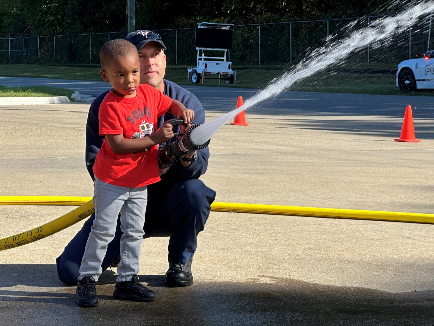 A firefighter and child test a fire hose.