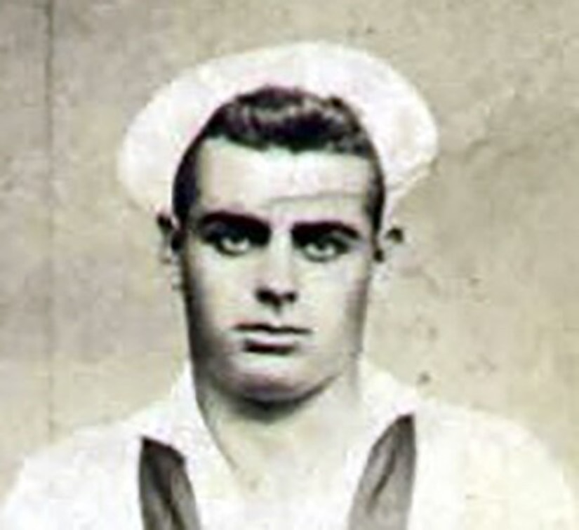 A man in uniform and cap poses for a photo.