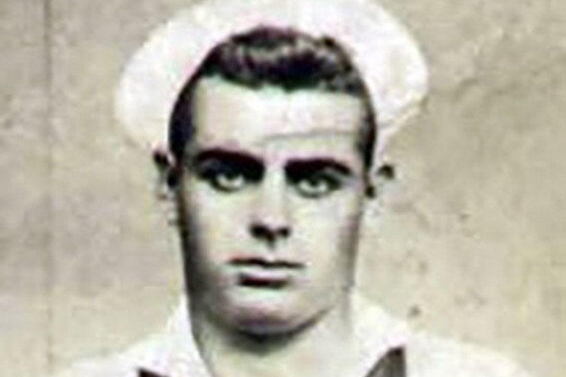 A man in uniform and cap poses for a photo.