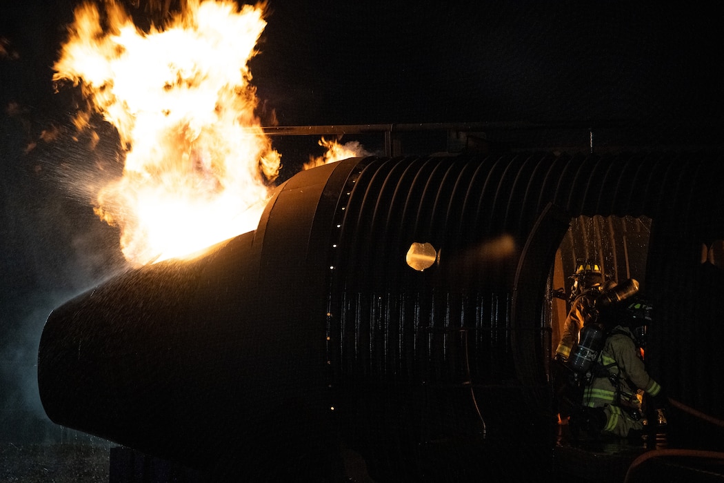 436th Civil Engineer Squadron firefighters extinguish a fire during a night live fire training at Dover Air Force Base, Delaware, Oct. 15, 2024. The 436th CES Fire and Emergency Services team conducts live fire training on a quarterly basis to maintain fire-fighting techniques and skills. (U.S. Air Force photo by Staff Sgt. Marco A. Gomez)