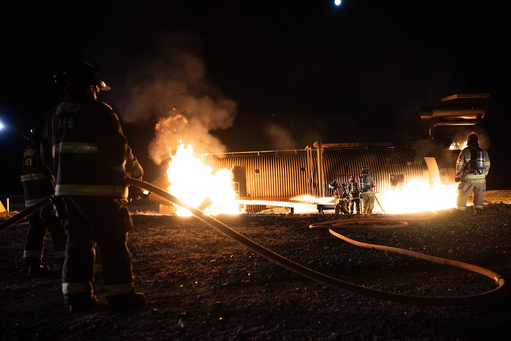 436th Civil Engineer Squadron firefighters extinguish a fire during a night live fire training at Dover Air Force Base, Delaware, Oct. 15, 2024. The 436th CES Fire and Emergency Services team conducts live fire training on a quarterly basis to maintain fire-fighting techniques and skills. (U.S. Air Force photo by Staff Sgt. Marco A. Gomez)