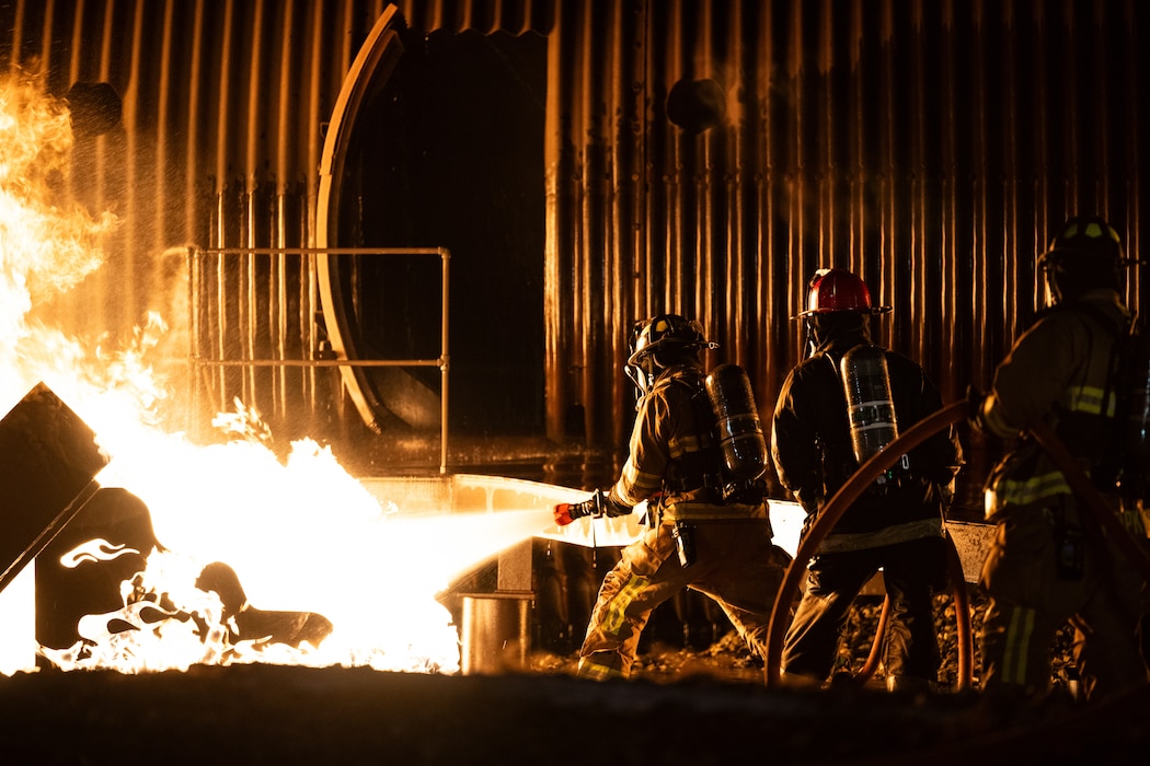 436th Civil Engineer Squadron firefighters extinguish a fire during a night live fire training at Dover Air Force Base, Delaware, Oct. 15, 2024. The 436th CES Fire and Emergency Services team conducts live fire training on a quarterly basis to maintain fire-fighting techniques and skills. (U.S. Air Force photo by Staff Sgt. Marco A. Gomez)