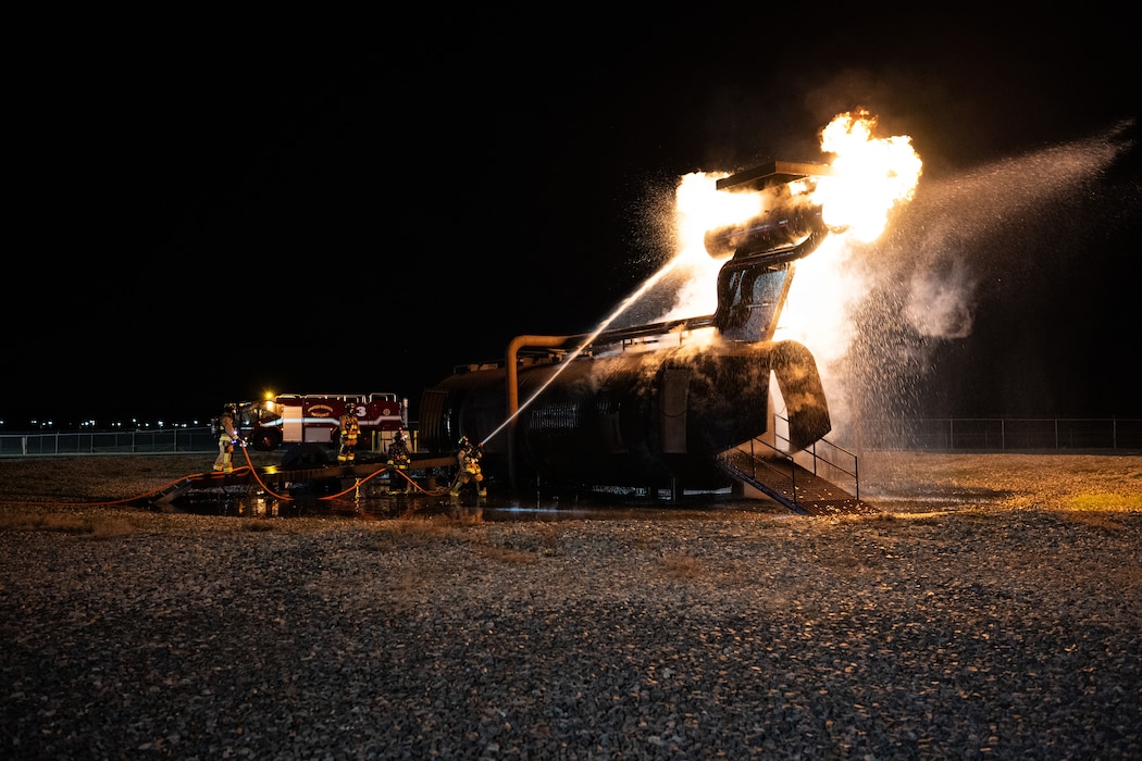 436th Civil Engineer Squadron firefighters extinguish a fire during a night live fire training at Dover Air Force Base, Delaware, Oct. 15, 2024. The 436th CES Fire and Emergency Services team conducts live fire training on a quarterly basis to maintain fire-fighting techniques and skills. (U.S. Air Force photo by Staff Sgt. Marco A. Gomez)