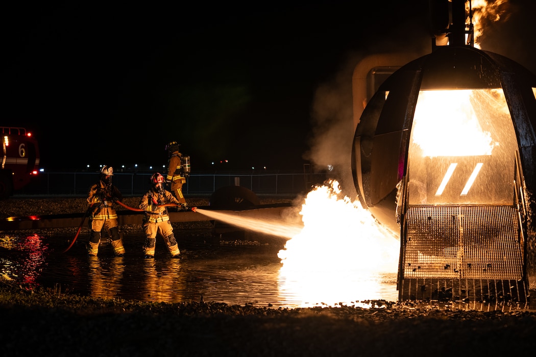 436th Civil Engineer Squadron firefighters extinguish a fire during a night live fire training at Dover Air Force Base, Delaware, Oct. 15, 2024. The 436th CES Fire and Emergency Services team conducts live fire training on a quarterly basis to maintain fire-fighting techniques and skills. (U.S. Air Force photo by Staff Sgt. Marco A. Gomez)