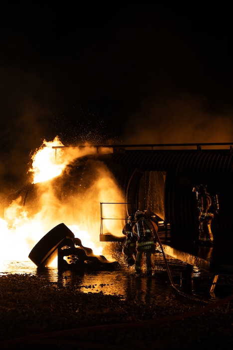 436th Civil Engineer Squadron firefighters extinguish a fire during a night live fire training at Dover Air Force Base, Delaware, Oct. 15, 2024. The 436th CES Fire and Emergency Services team conducts live fire training on a quarterly basis to maintain fire-fighting techniques and skills. (U.S. Air Force photo by Staff Sgt. Marco A. Gomez)