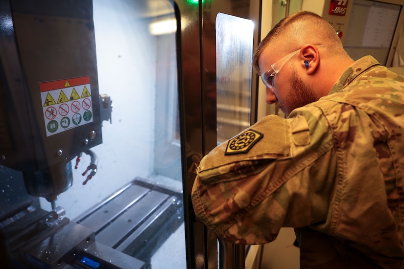 U.S. Army Sgt. Gerhard Abramat, ARCENT Innovation and Manufacturing Center (AIM-C) NCO, observes the Computer Numerical Controlled (CNC) Mill at the AIM-C in the U.S. Central Command area of responsibility.